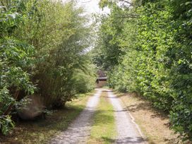 A gravel path surrounded by trees leading to a shed at Tigley Meadow Coach House in Totnes