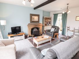 A living room with a fireplace and television at School Cottage in Windermere