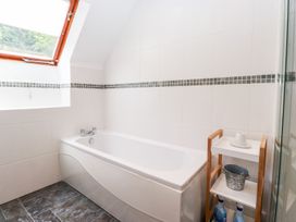 A bathroom with a bathtub and shelf at School Cottage in Windermere