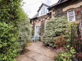 A garden featuring a stone wall, patio and garden chairs at School Cottage in Windermere
