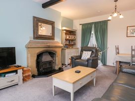 A living room with a fireplace and television at School Cottage in Troutbeck Bridge near Windermere
