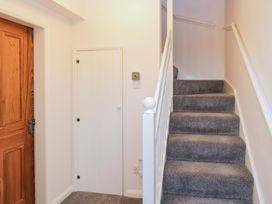 A hallway with a staircase and doors at School Cottage in Troutbeck Bridge near Windermere