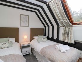 A bedroom with two beds and a nightstand at School Cottage in Troutbeck Bridge near Windermere