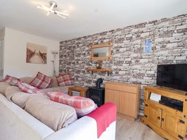 A living room with a sofa, television, and decorative wall at Boo’s Bungalow in Callington near Gunnislake