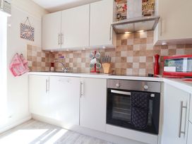 A kitchen with cabinets, oven, sink, and utensils at Boo’s Bungalow in Callington near Gunnislake