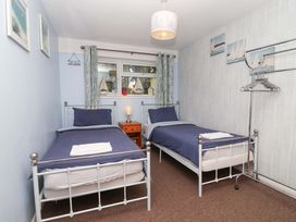 A bedroom with two single beds and a nightstand at Boo’s Bungalow in Callington near Gunnislake