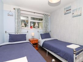 A bedroom with two beds and a window at Boo’s Bungalow in Callington near Gunnislake