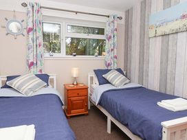 A bedroom with two single beds and a nightstand at Boo’s Bungalow near Gunnislake