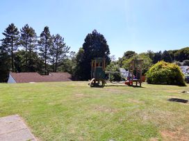 A garden with a playground and trees at Boo’s Bungalow in Callington near Gunnislake
