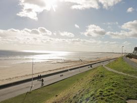 A beach with people walking along a pathway at Atelier in Bridlington