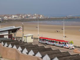 A beach with train and beach huts at Atelier in Bridlington