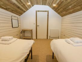 A bedroom with two beds and a wooden table at Gowan Brae in Criccieth