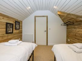 A bedroom with two beds and a wooden wall at Gowan Brae in Criccieth