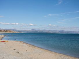 A beach with water and mountains in the background at Gowan Brae in Criccieth