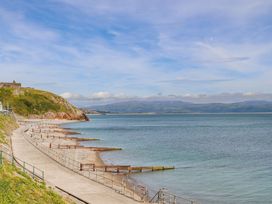 A beach with a pathway and pier at Gowan Brae Criccieth