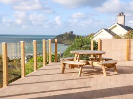 A deck with a wooden table and benches overlooking the ocean at Gowan Brae in Criccieth