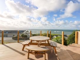 An outdoor seating area with a table and benches overlooking the sea at Gowan Brae in Criccieth