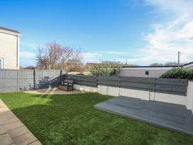 A garden with grass and a wooden deck at Penrhos Walks in Holyhead