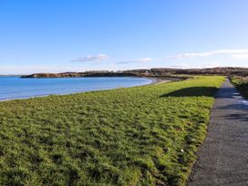 A pathway along the shore with grass and water at Penrhos Walks Holyhead