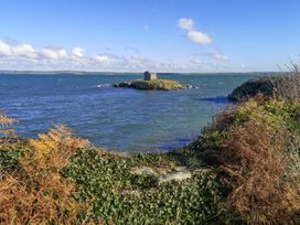 A coastal view with an island and a stone structure at Penrhos Walks Holyhead