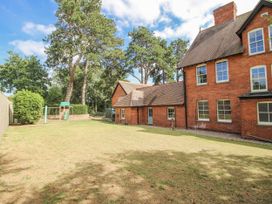 A garden with a brown brick building and trees at The Old Vicarage Kimbolton near Leominster