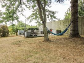 A garden with a hammock between trees and a patio area at The Old Vicarage Kimbolton near Leominster