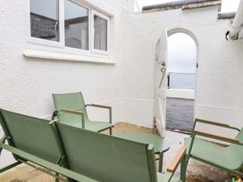 An outdoor area with green chairs and a table at Ocean Edge in Sennen Cove