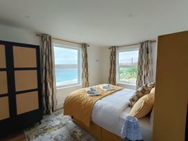 A bedroom with a bed and windows at Ocean Edge in Sennen Cove