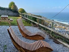 An outdoor area with wooden loungers and a picnic table at Ocean Edge in Sennen Cove
