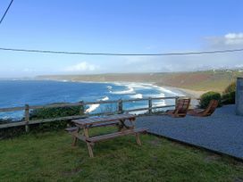 An outdoor area with a picnic table and deck chairs overlooking the ocean at Ocean Edge in Sennen Cove