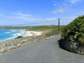 A view of a beach and ocean with a road leading to it at Ocean Edge Sennen Cove