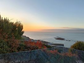 A view of the ocean and sunset with plants and rocks at Ocean Edge Sennen Cove