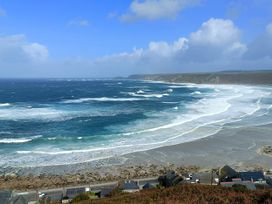 A view of waves and beach with houses at Ocean Edge in Sennen Cove