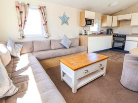 A living room with a sofa and kitchen appliances at Willerby Aurora B14 Towyn