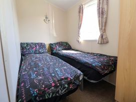 A bedroom with two single beds and a window at Willerby Aurora B14 Towyn