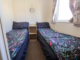 A bedroom with two single beds and a nightstand at Willerby Aurora B14 Towyn