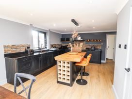 A kitchen with a large island and bar stools at Holly Farm near Brantham