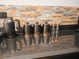 A kitchen countertop with a kettle and storage containers at Holly Farm near Brantham