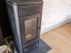 A stove with a glass door in a living room at Holly Farm near Brantham