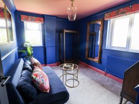 A sitting room with a blue sofa and plants at Holly Farm near Brantham