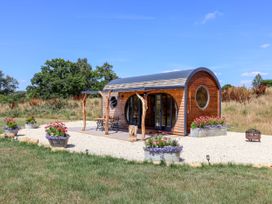 A wooden cabin with outdoor seating and flower planters at Bugley Pools Hideaway in Bugley near Gillingham