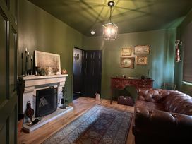 A living room with a fireplace, couch, and table at The Garden Cottage and Carriage House Annagry, County Donegal