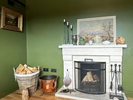 A living room with a fireplace and wooden logs at The Garden Cottage and Carriage House in Annagry, County Donegal