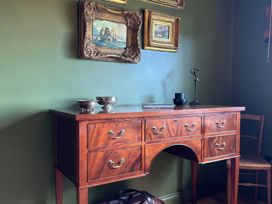 A sideboard with framed paintings and a sculpture at The Garden Cottage and Carriage House, Annagry, County Donegal