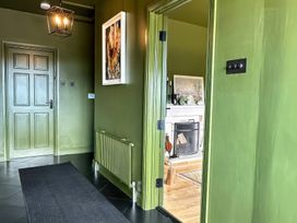 A hallway with a door and a view into a living room at The Garden Cottage and Carriage House Annagry, County Donegal
