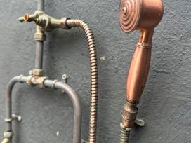 A spray nozzle and piping in a bathroom at The Garden Cottage and Carriage House Annagry, County Donegal