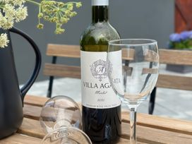 A wine bottle and glass on a table at The Garden Cottage and Carriage House Annagry, County Donegal