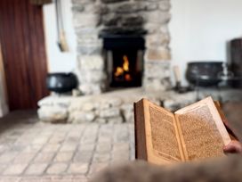 A living room with a fireplace and an open book at Cobble Stone Cottage near Leabgarrow, County Donegal