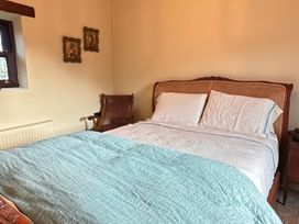 A bedroom with a bed and an armchair at Cobble Stone Cottage near Leabgarrow, County Donegal