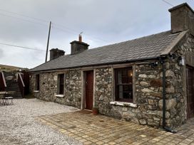 A stone cottage with a paved area and outdoor furniture at Cobble Stone Cottage near Leabgarrow, County Donegal